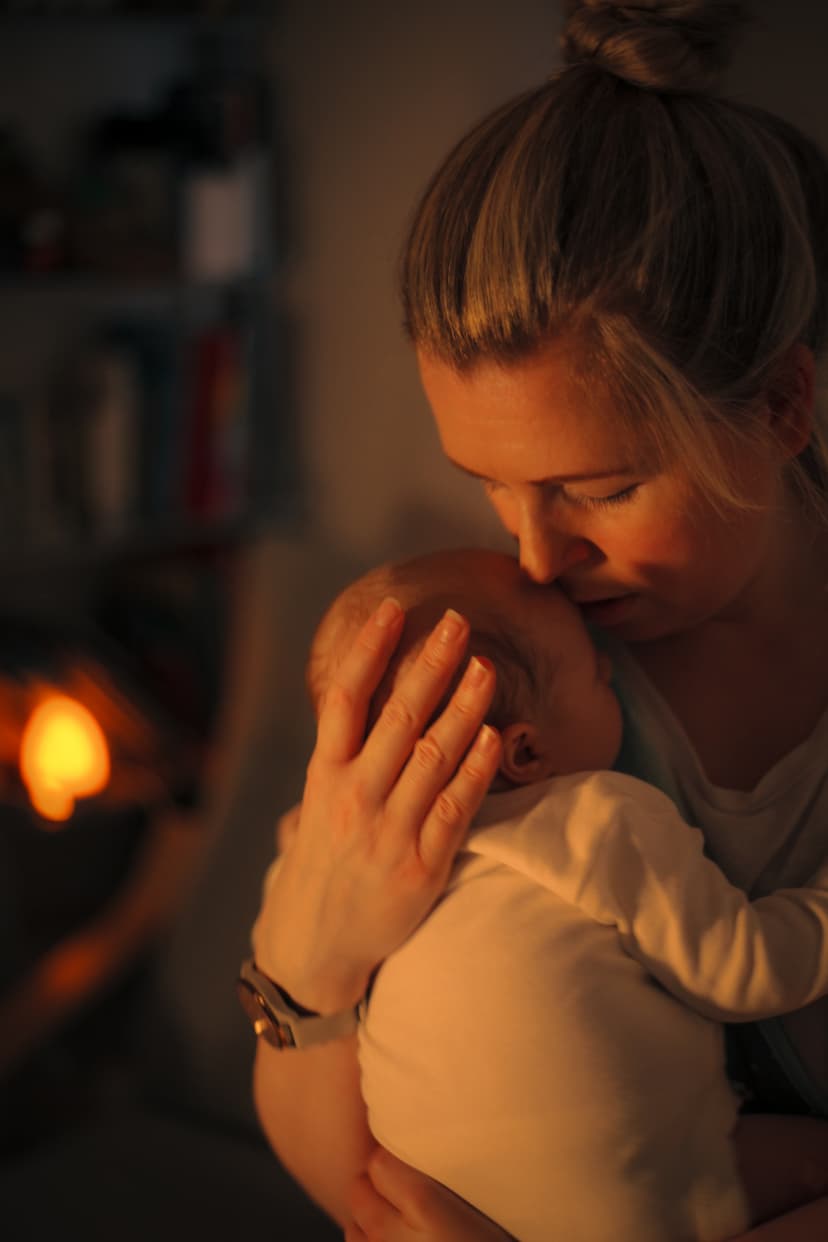 Parent cuddling baby in soft evening light